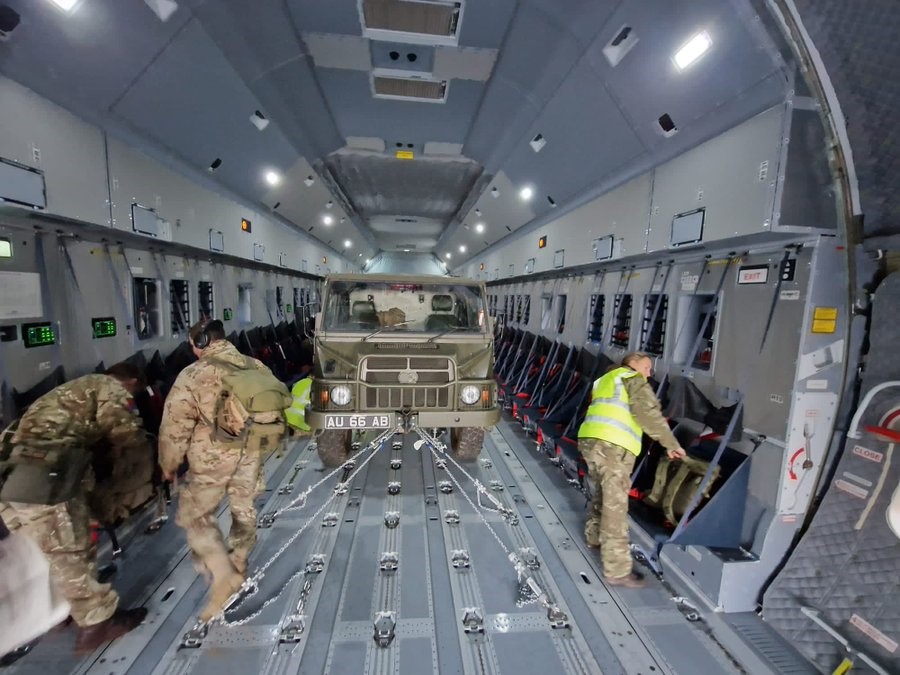 Photo - Personnel working within the Atlas aircraft, preparing to unload a vehicle and trailer.